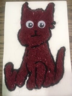 Handmade dog with red-brown fur made from yarn. Cute wobbly eyes