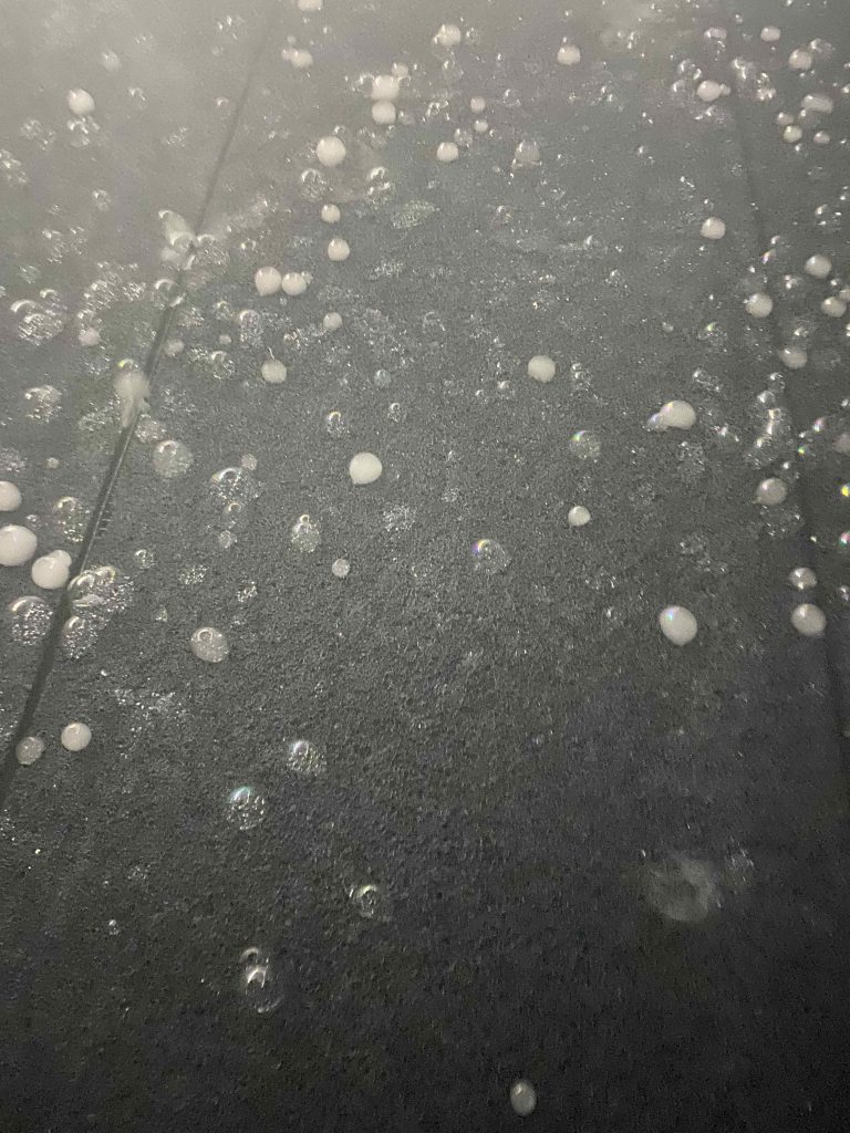Dim white light illuminates the soap bubbles better. Visitors reach out to pop the bubbles