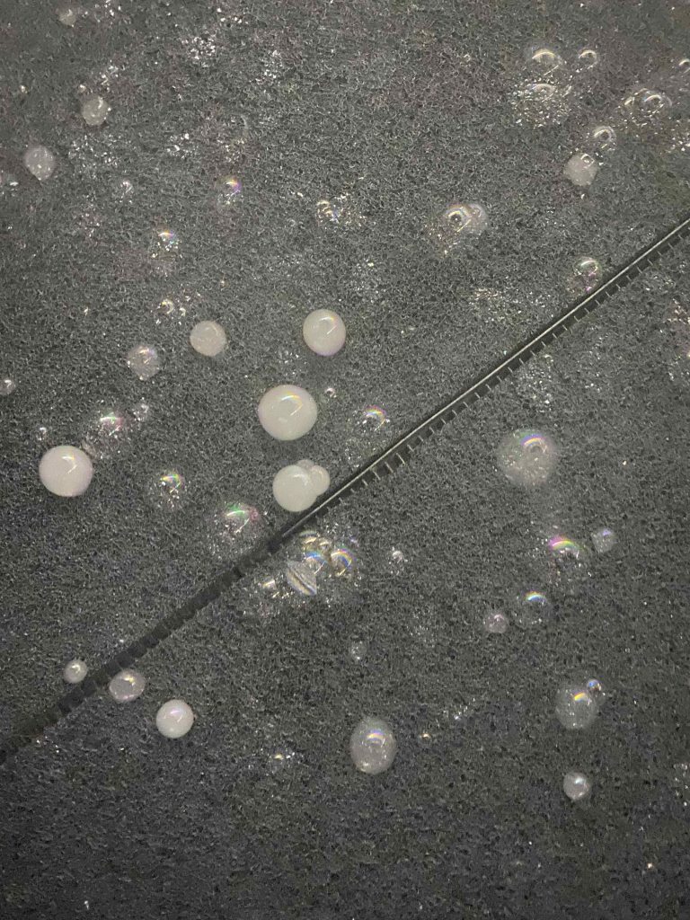 Some soap bubbles look white while others appear transparent. There are various sizes of bubbles 