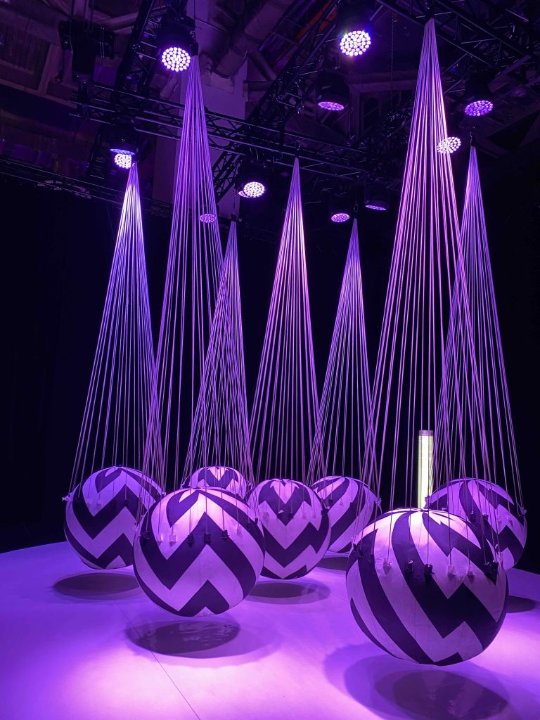 This is titled SWING; some balloons hung from the ceiling. When visitor walks in-between spheres, they move, showing interactive movements. Visitors trust the gentle movements replicating action and reaction, like in life