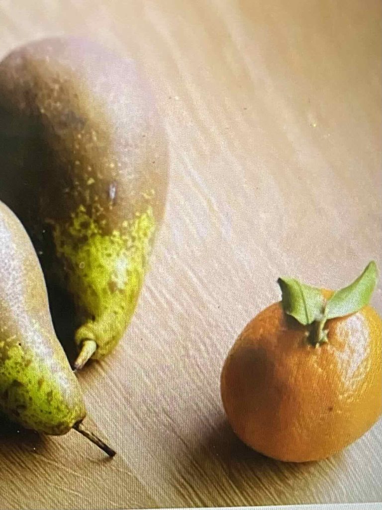 Relative size of a clementine, shown next to pears. Its skin is peel-able, different from an orange.